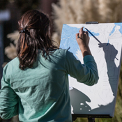 A woman paints a picture on an easel. 